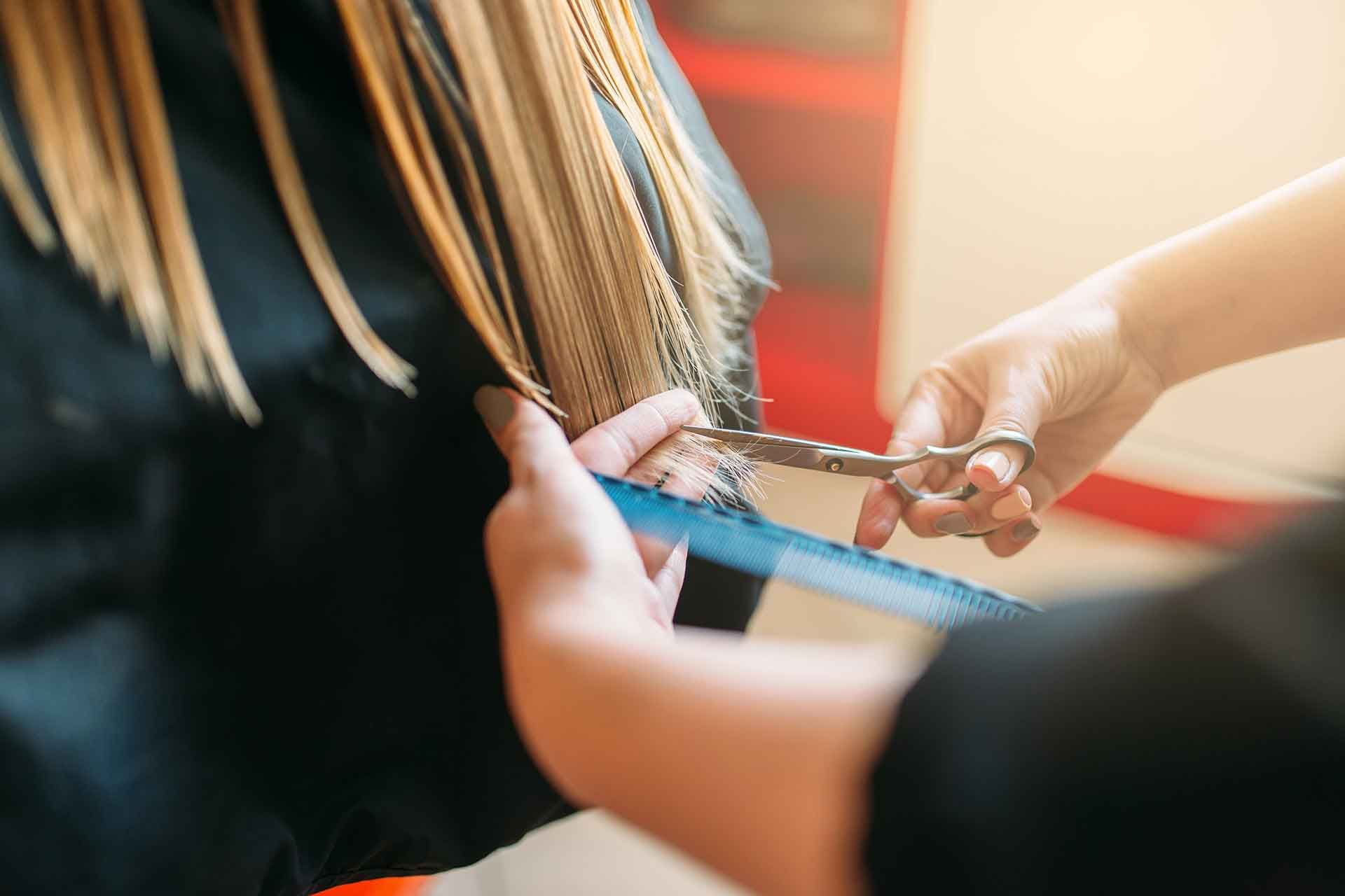 hairdresser-with-scissors-in-hand-cuts-female-hair-